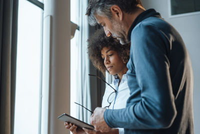 Multiracial business colleagues discussing over tablet computer in office