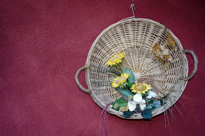 Close-up of flowers in wicker basket hanging on red velvet