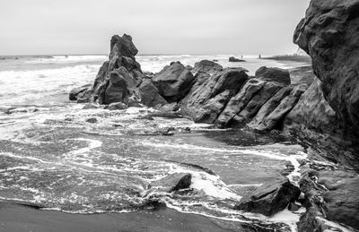 Rock formation at beach against sky