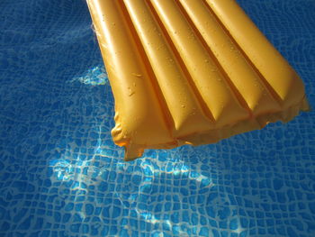 High angle view of yellow pool raft floating on water