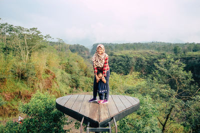 Full length of mother and daughter standing at observation point in forest