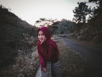 Portrait of smiling young woman standing on land