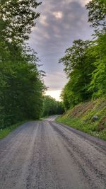 Road passing through landscape against cloudy sky