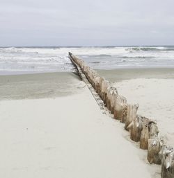 Wooden posts on beach against sky