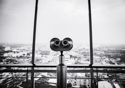 Close-up of coin-operated binoculars against buildings in city