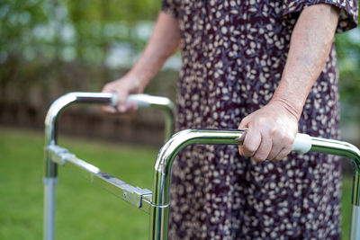 Asian senior woman patient walk with walker in park, healthy strong medical concept.