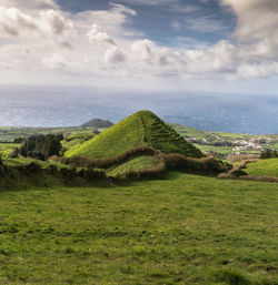 Scenic view of green landscape against cloudy sky