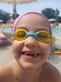 Portrait of smiling girl wearing swimming goggles at beach