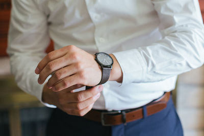 Midsection of businessman wearing wristwatch at home