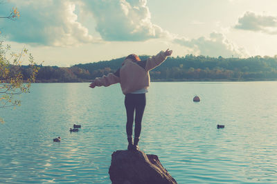 Rear view of man standing in lake against sky