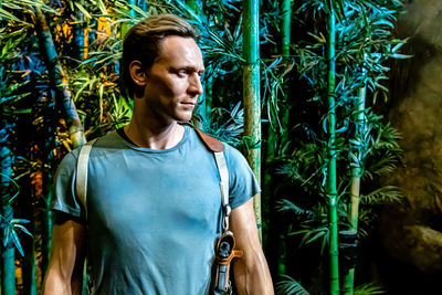 Portrait of young man standing against plants