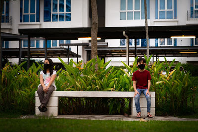 Two asian children wearing mask standing off 1 meter from others keeping distancing. new normal.