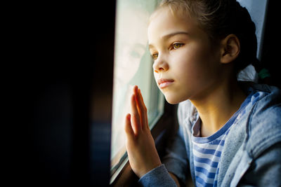 Close-up of girl looking away through window