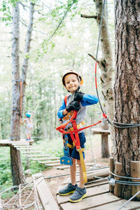 Full length of boy standing against trees