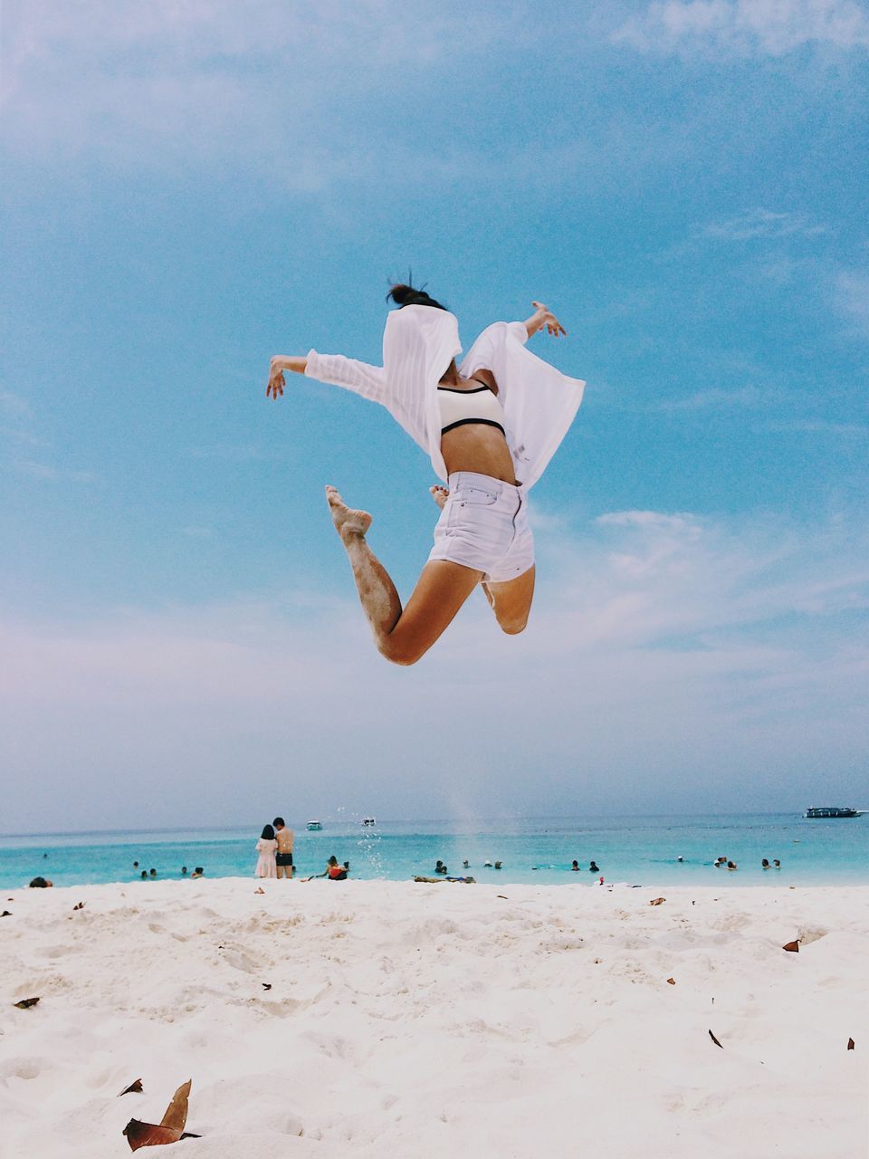 MAN JUMPING ON BEACH AGAINST SKY