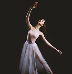 Young woman dancing against black background