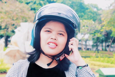 Portrait of young woman wearing crash helmet while standing outdoors