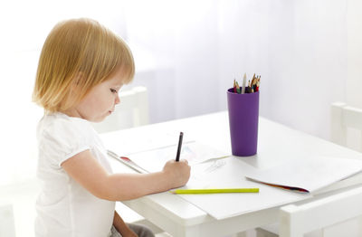 Side view of a girl holding camera on table