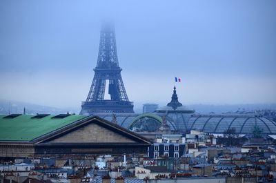 Eiffel tower by buildings against sky