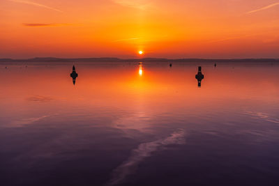 Silhouette person on sea against orange sky during sunset