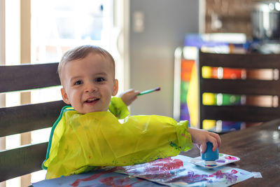 Portrait of cute boy sitting on table at home