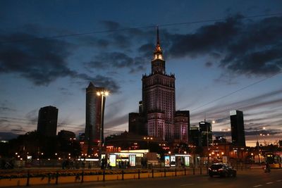 Palace of culture and science by city street against sky at dusk