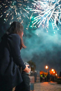 Rear view of woman looking at firework display at night