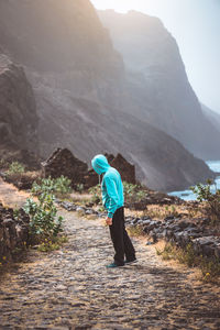 Rear view of man walking on mountain against sky