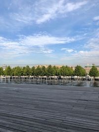 Footpath by river in city against sky