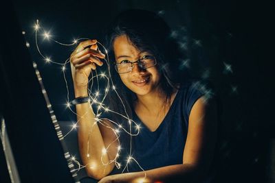 Portrait of young woman with illuminated lighting equipment at night