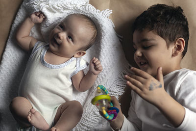 High angle view of cute brothers lying on blanket