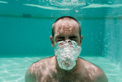 Portrait of shirtless man swimming in pool