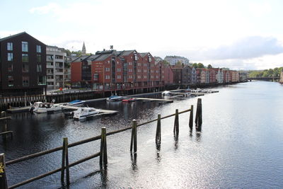 Sailboats moored on river by buildings in city against sky