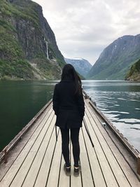 Rear view of woman standing on lake against mountain