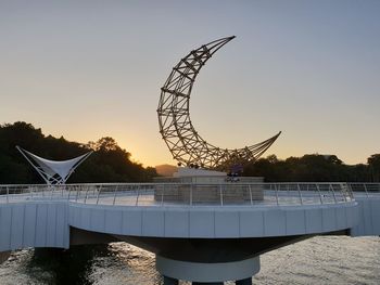 People at amusement park against sky during sunset