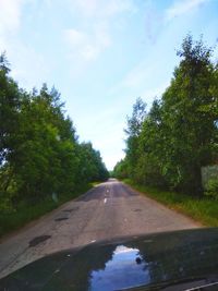 Road amidst trees against sky seen through car windshield