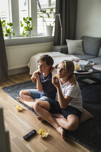 Brothers eating potato chips while watching tv in living room