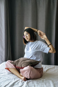 Young woman sitting on bed at home