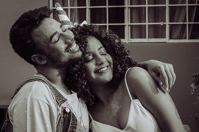 Happy young couple smiling with eyes closed against house