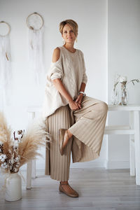 Beautiful woman interior designer decorates a new home, sitting in a beige sweater and pants