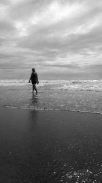 Rear view of woman on beach against sky