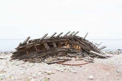 Abandoned wooden structure on beach against clear sky