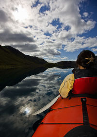 Woman rowing sea kayak on still lake in central iceland