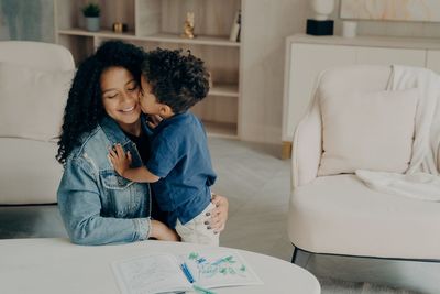 Cute kid kissing mother at home