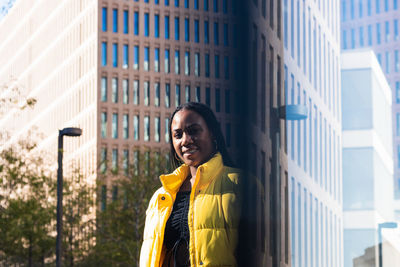 Portrait of smiling woman standing against building in city