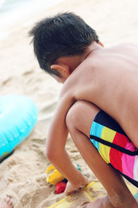 Rear view of shirtless boy playing at beach