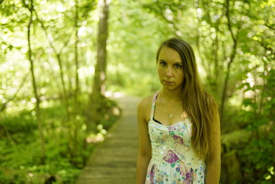 Portrait of woman standing against plants in forest