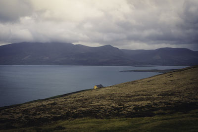 Scenic view of an orange house on the side of the hill, overlooking a lake or ocean. 