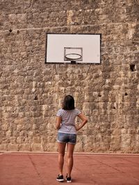 Rear view of man standing on basketball hoop