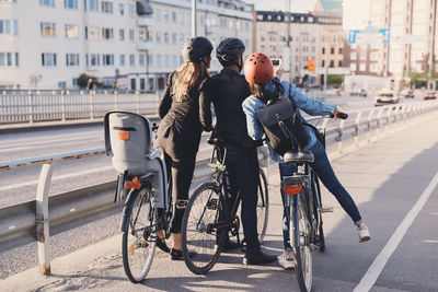 Rear view of man taking selfie with female friends with bicycles on street